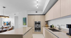 A modern kitchen with a central island, stainless steel appliances, and light wood cabinetry. - Insane Ocean View Balcony Beachfront Resort Pool (Hollywood)