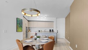 Una cocina moderna con una isla central, un comedor con una mesa redonda e iluminación colgante contemporánea.