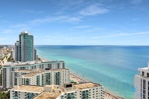 A coastal cityscape with high-rise buildings, a beach, and clear blue waters. - Insane Ocean View Balcony Beachfront Resort Pool (Hollywood)