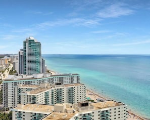 A coastal cityscape with high-rise buildings, a beach, and clear blue waters.