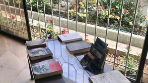 A table with books arranged in the center of a room with a view of a garden through a metal gate. - Villa Garza Inn (Guayaquil)