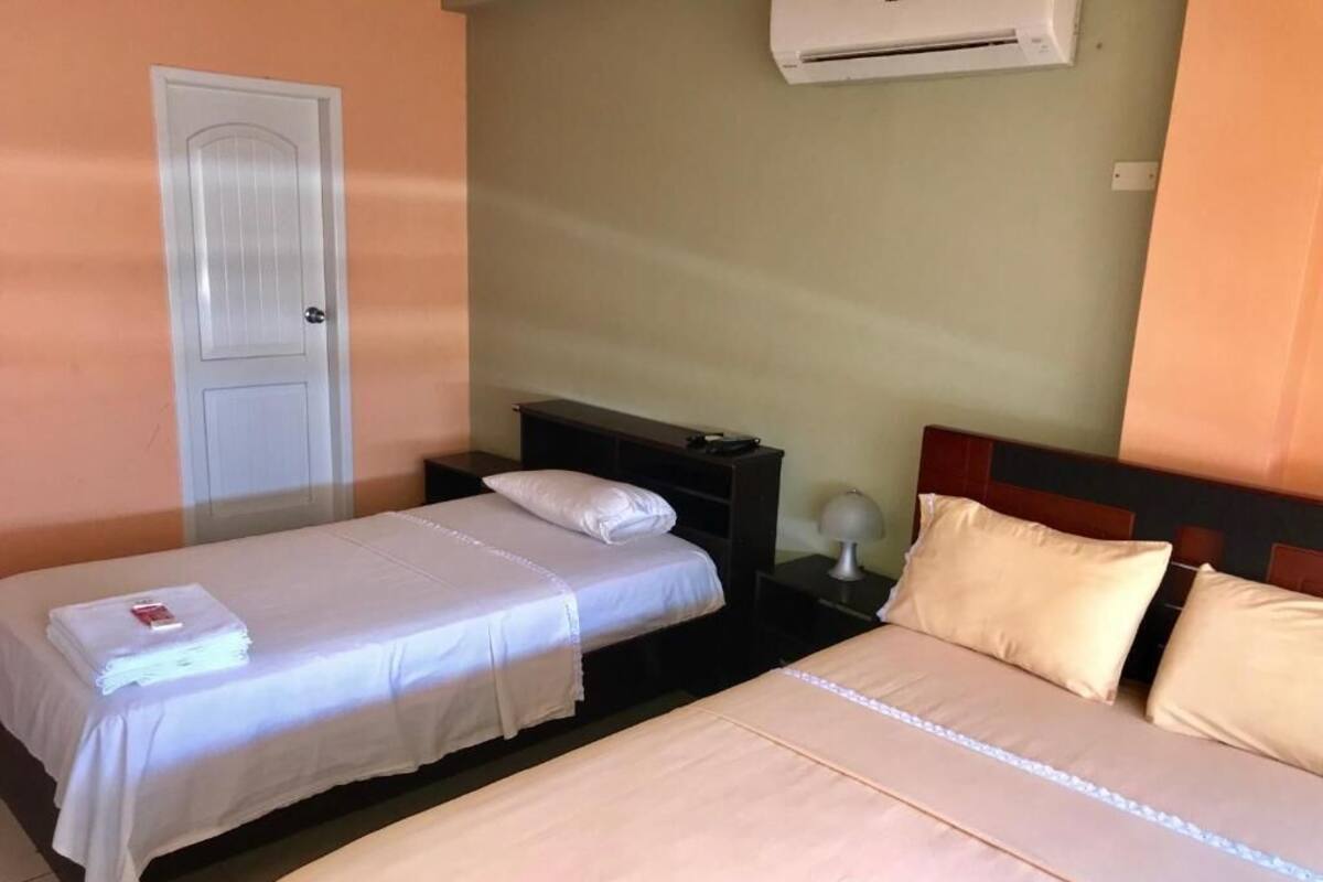 Une chambre d’hôtel avec deux lits, une porte, une table de chevet et un appareil de climatisation.