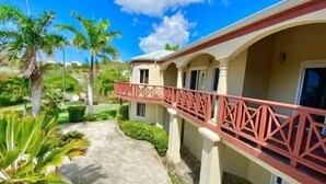 A resort with a covered walkway, palm trees, and a clear blue sky.