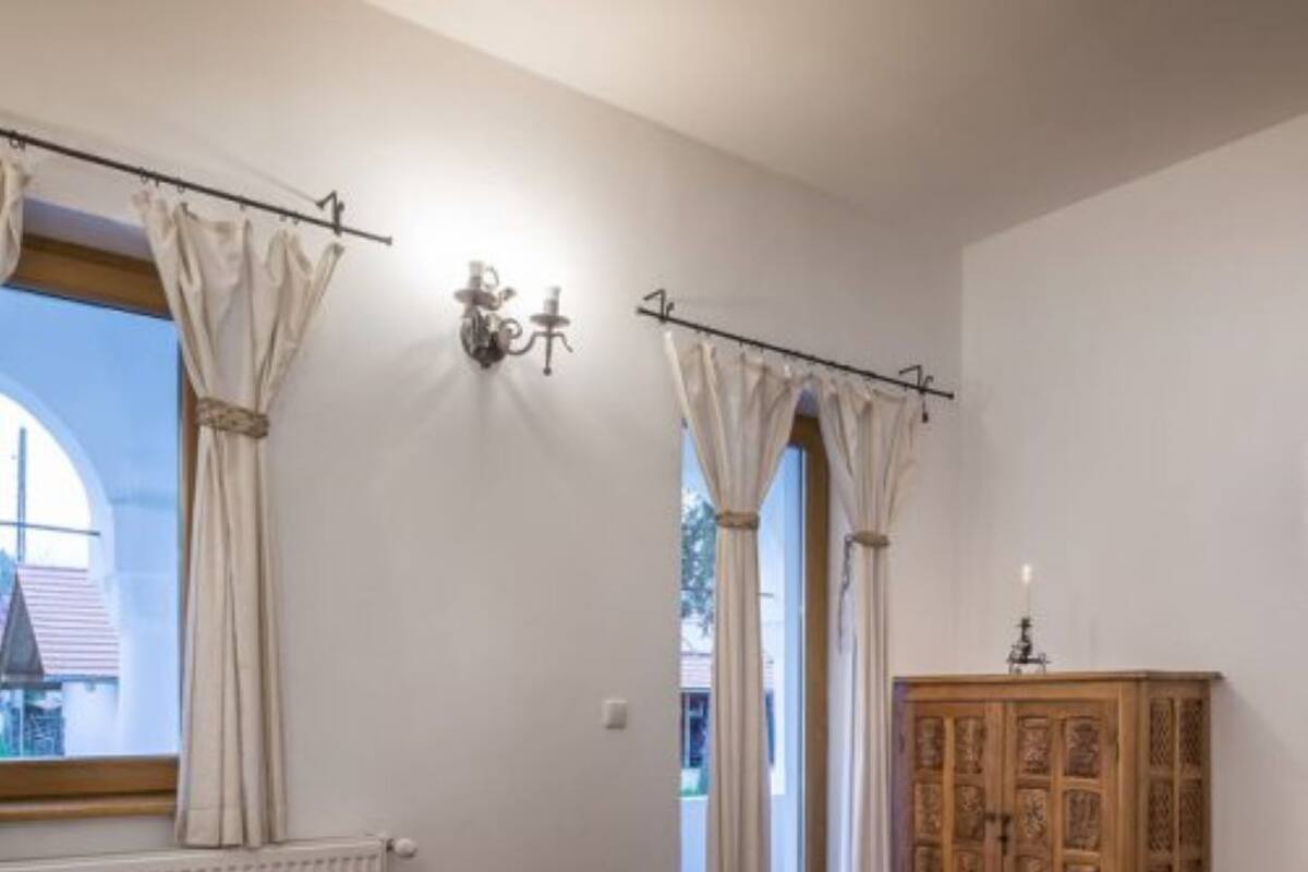 A bedroom with two beds, a wooden cabinet, and a window with curtains.