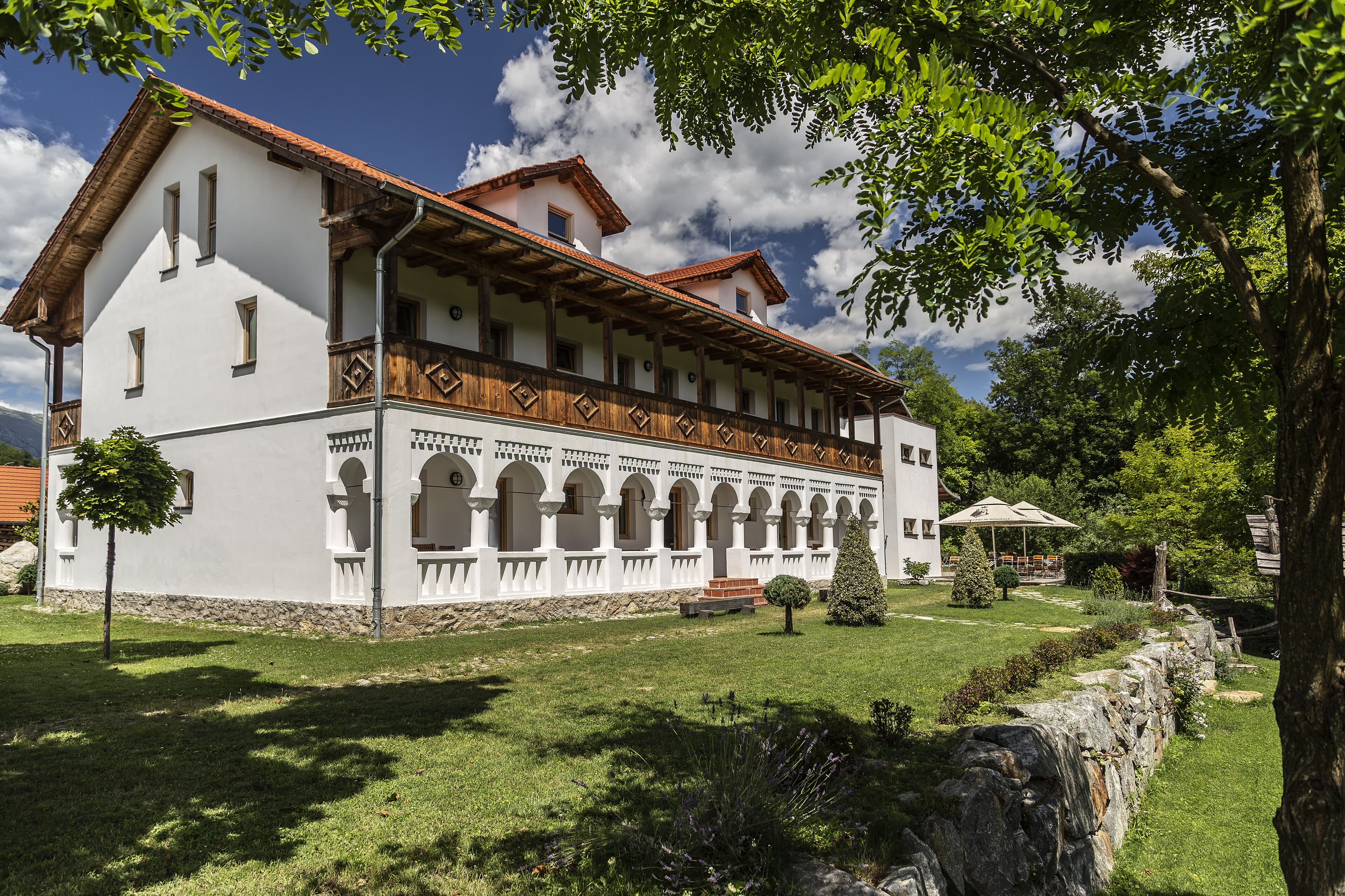 Ein traditionelles Gebäude mit weißer Fassade, hölzernen Balkonen und einem Steinuntergrund.