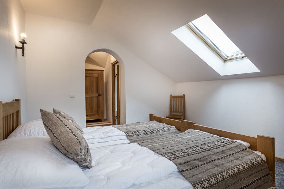 A bedroom with a skylight, a bed with patterned bedding, and a wooden headboard.