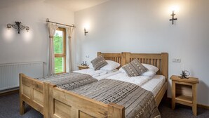 A double wooden bed with a patterned bedspread, two bedside tables, a window with curtains, and wall-mounted lighting. - Hanul Vatra (Costesti)