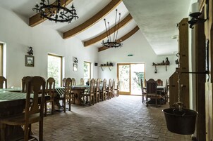 Un comedor con mesas y sillas de madera, un candelabro y una olla colgante.