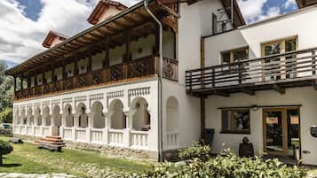 A traditional building with a balcony, arched windows, and a stone pathway.