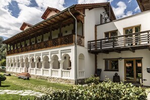 A traditional building with a balcony, arched windows, and a stone pathway. - Hanul Vatra (Costesti)