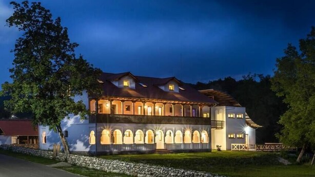 A two-story building with a symmetrical facade, arched windows, and a central entrance. - Hanul Vatra (Costesti)