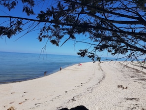 A beach with clear blue water, a sandy shore, and a few people.