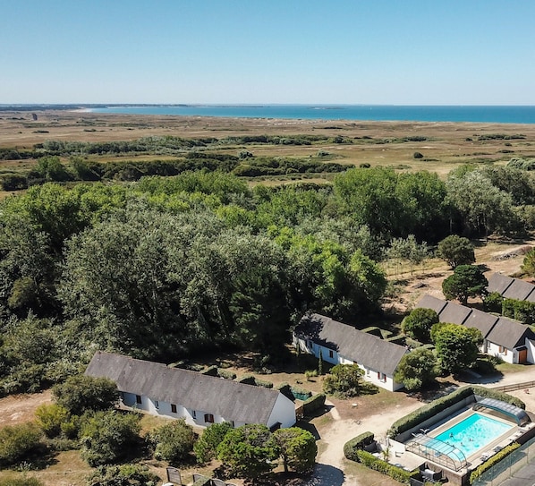A residential area with multiple houses, a swimming pool, and a view of the sea.