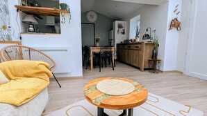 Un salon moderne avec un canapé jaune, une table ronde en bois et un coin repas comprenant un buffet en bois et des chaises.