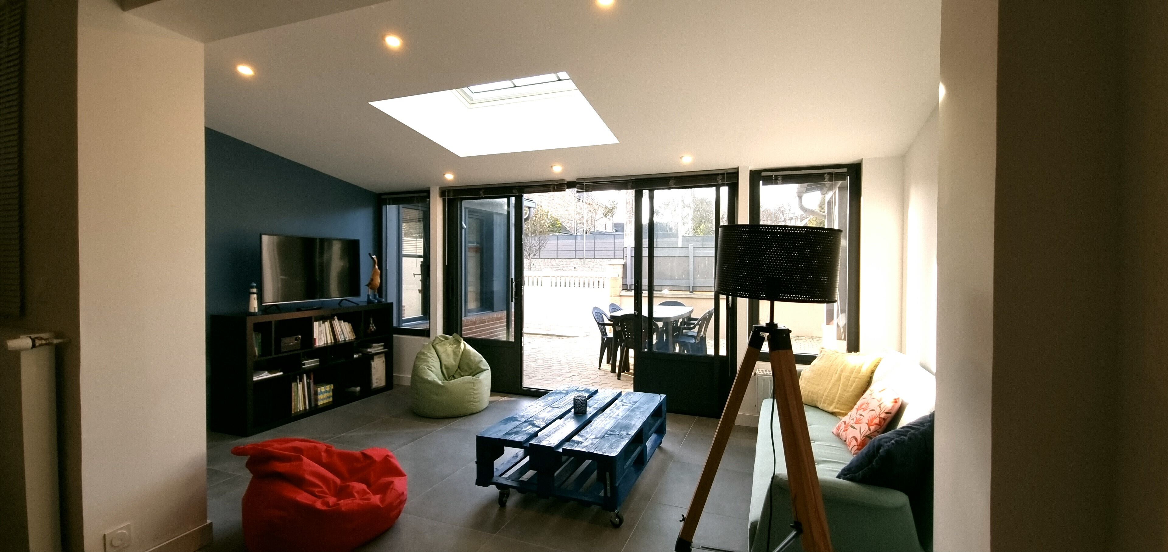 Een moderne woonkamer met een flatscreen televisie, een kruikzak, een houten tafel en een statief.