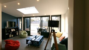 Un salon moderne avec un téléviseur à écran plat, un fauteuil poire, une table en bois et un trépied.
