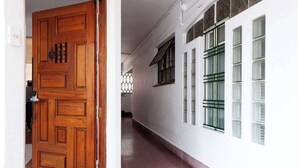 A hallway with a wooden door, a window with green frames, and a white wall with a green directional sign. - w* | Elegant & Bright 2BR in Prime Polanco (Ciudad de México)