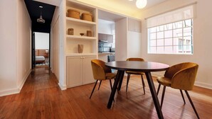 A modern kitchen with white cabinets, a dining table with four chairs, and a window with a view of buildings. - w* | Elegant & Bright 2BR in Prime Polanco (Ciudad de México)