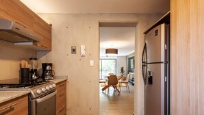 A modern kitchen with a built-in oven, a coffee maker, and a refrigerator. - w* | Refined 2BR w/ Balcony in Parque España (Ciudad de México)