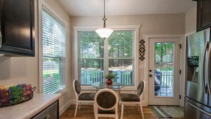 A kitchen with a dining table, chairs, a refrigerator, and a window with blinds. - Be our guest-3-bedroom house in a great location! (Fletcher)