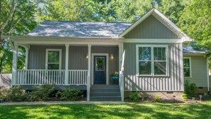 A single-story house with a front porch, a dark front door, and a small garden area. - Be our guest-3-bedroom house in a great location! (Fletcher)