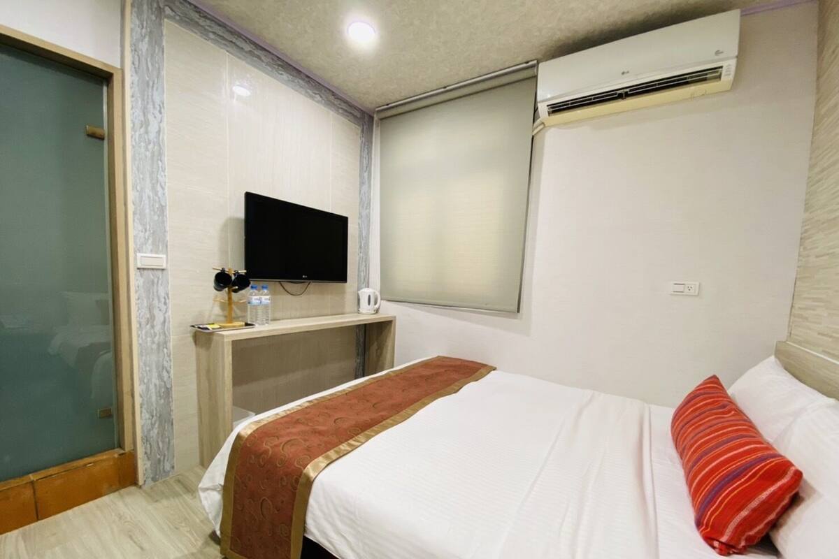 Ein Hotelzimmer mit einem Bett, einem Schreibtisch, einem Fernseher und einer Klimaanlage.