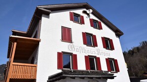 En bygning med hvid facade og røde skodder, med en balkon og et skilt der siger "Softhaus Rone".