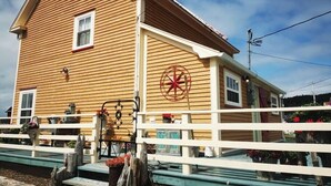 Un bâtiment en bois avec un porche blanc, une décoration en forme d’étoile rouge et une petite fenêtre.