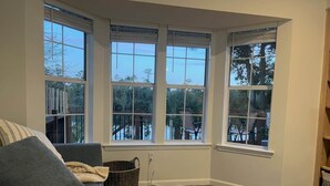 A living room with a gray couch, a woven basket, a patterned rug, and a glass table with two wooden trays. - The Robin House, Newly Furnished Lake Retreat Near Tybee Island & Savannah (Wilmington Island)
