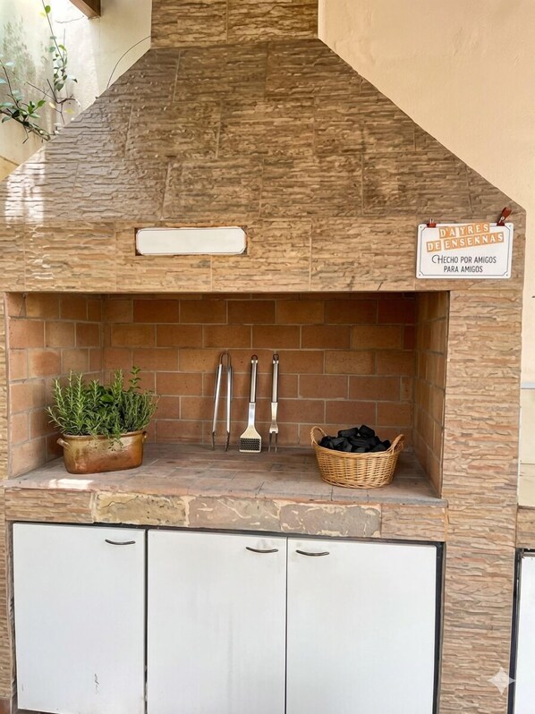 A kitchen with a stone backsplash, a sign indicating it's for friends, a potted plant, and cleaning tools. - Amplia e iluminada casa en Mendoza (Mendoza)