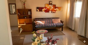 Ein Wohnzimmer mit einer Couch, einem Couchtisch, einem Bücherregal und einem großen floralen Wandbild.