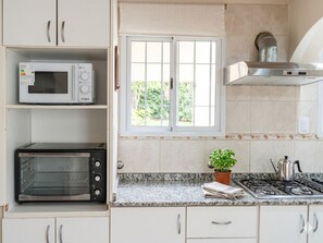 Cozinha equipada com micro-ondas, forno elétrico, fogão e janela com vista para o verde.