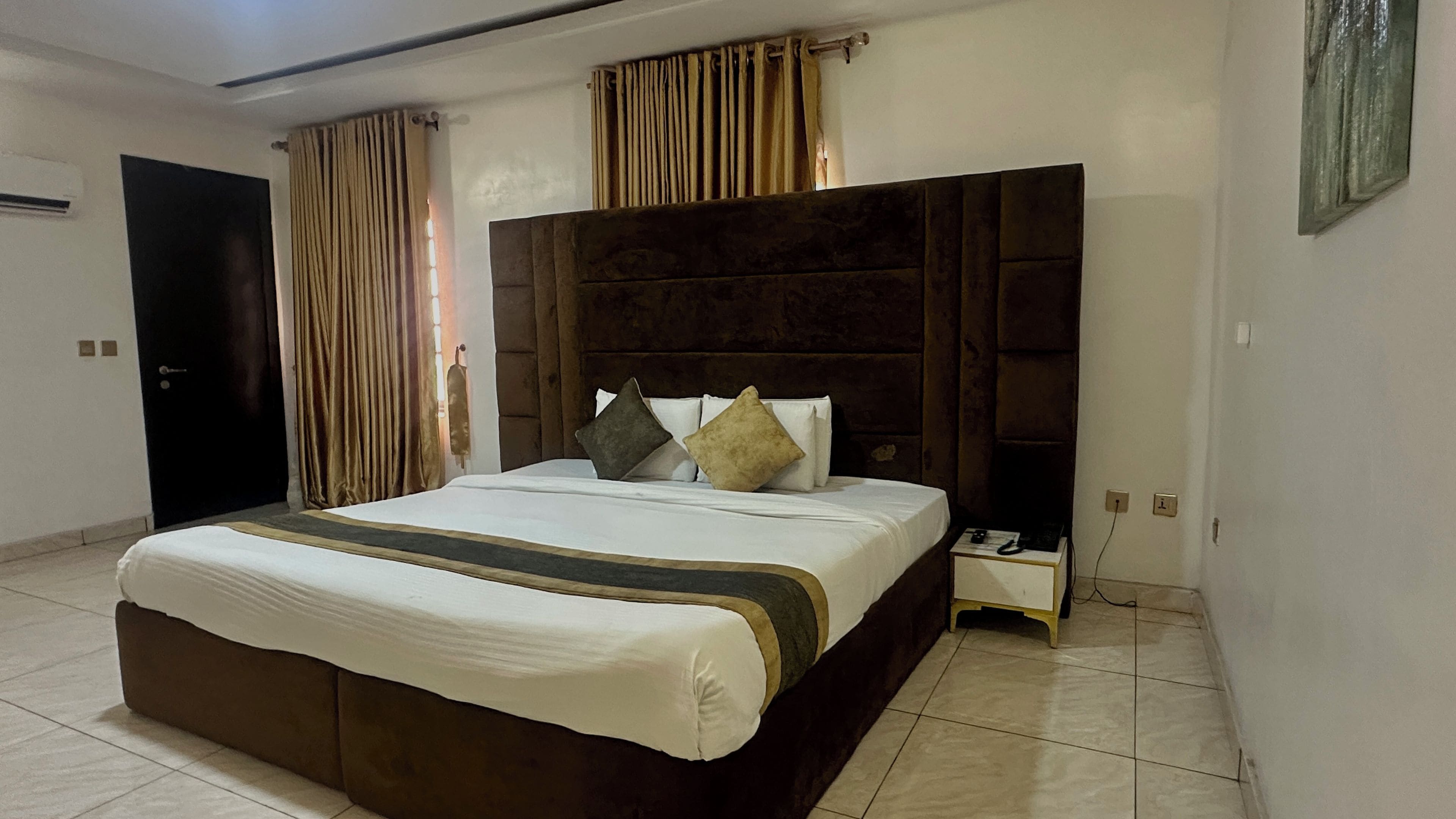 Una habitación de hotel con una cama grande, una mesita de noche y una puerta.