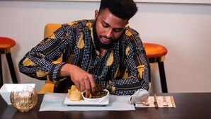 Une personne est assise à une table devant une assiette blanche remplie de nourriture, un petit bol et un élégant saladier en verre.