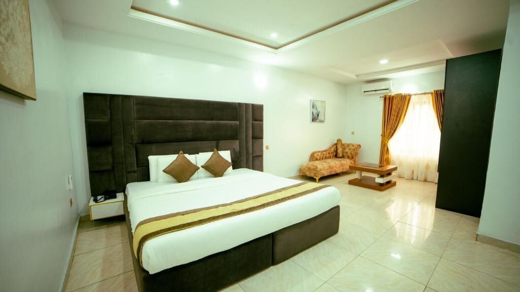 A modern hotel room with a large bed, a sofa, and a small table.