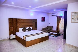 A bedroom with a wooden headboard bed, a small bedside table, a chair, and a nightstand.