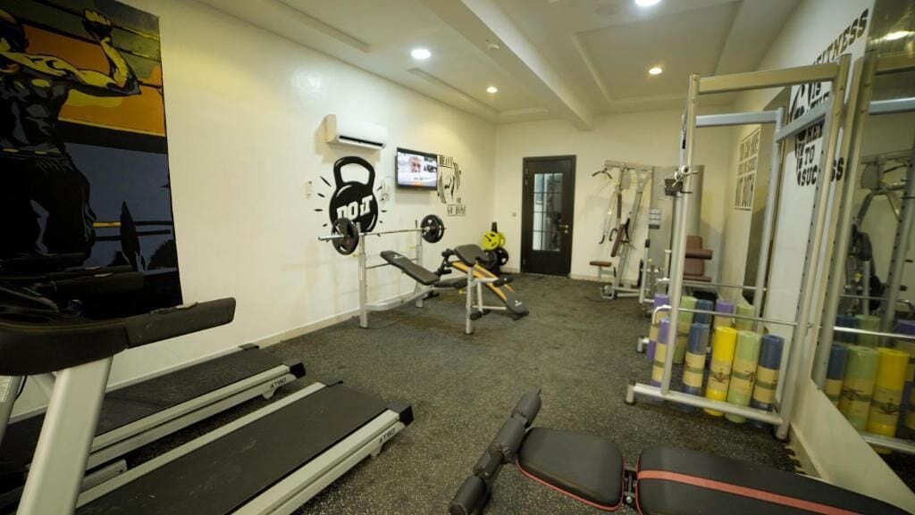 A gym with a treadmill, weight bench, kettlebell, and various exercise equipment.