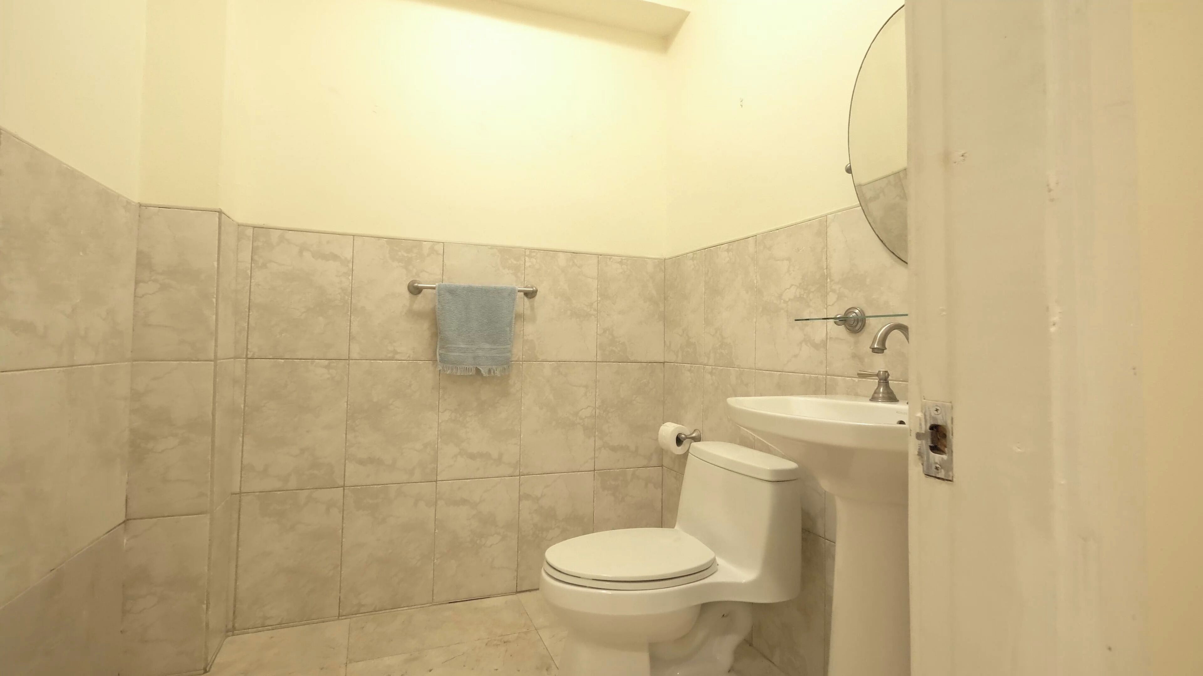 A small bathroom with a toilet, sink, and a towel hanging on a rack.