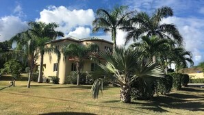 A two-story building with a flat roof, surrounded by palm trees and a well-maintained lawn.