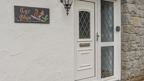 A white door with a glass panel, a metal nameplate with a squirrel illustration, and a stone wall.
