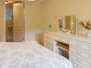 A bedroom with a bed, a dresser, a mirror, and a vase with flowers.