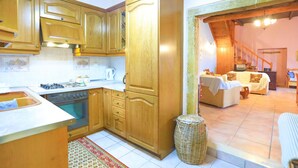 Una cucina con mobili in legno, un fornello e un lavello. Sul pavimento, un cesto di vimini e un tappeto decorato.