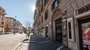 Vista de la calle con edificios, una acera y cielo despejado.
