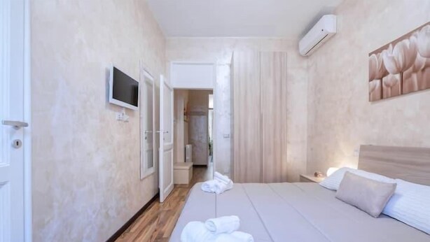 Una habitación de hotel con cama, televisión y aire acondicionado.