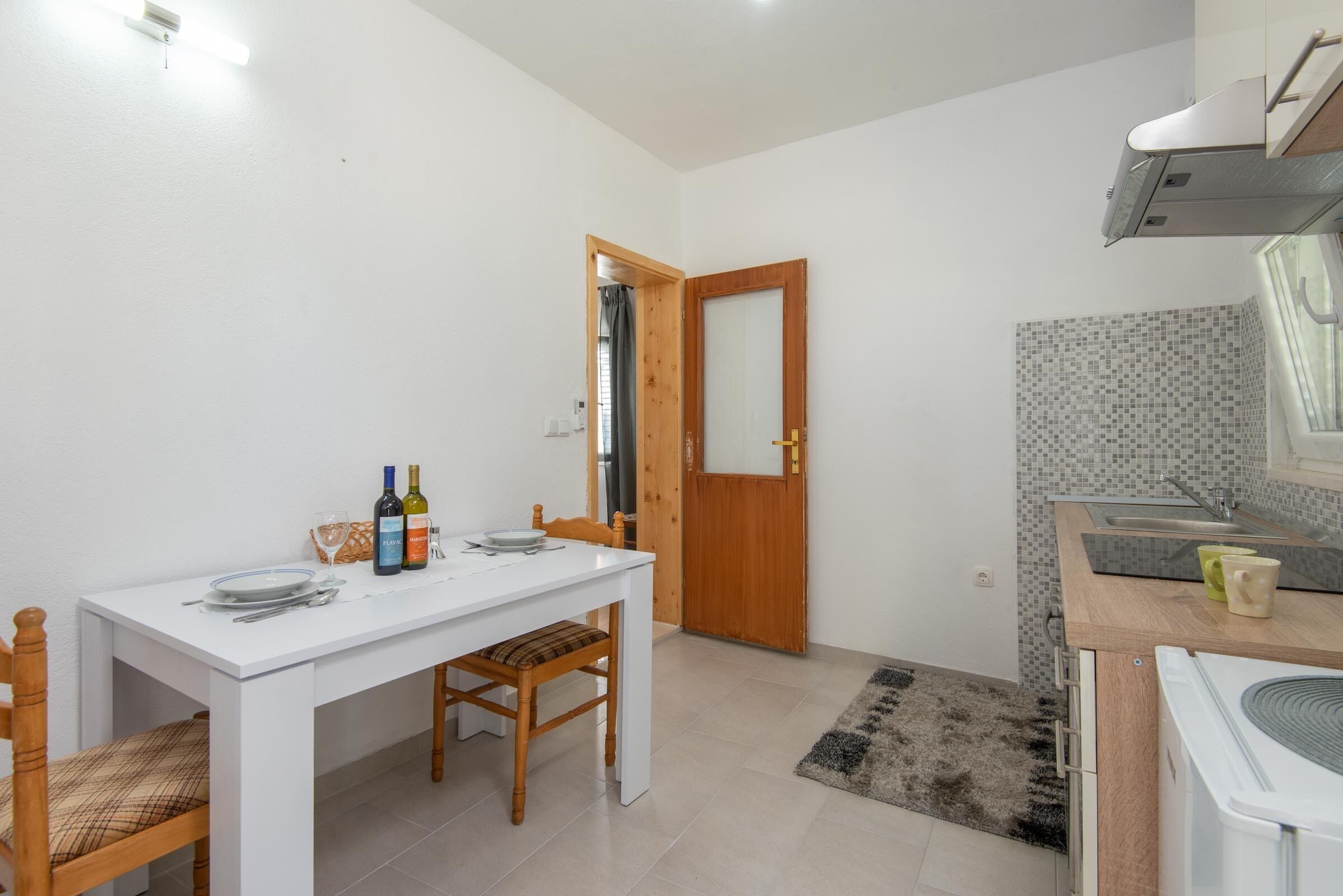 A compact kitchen with a dining area, a wooden door, and a tiled backsplash.