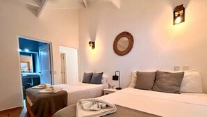 A hotel room with two beds, a mirror, a wall-mounted light, and a bathroom visible through an open door.