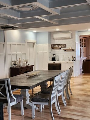 Una cocina moderna con una isla central, muebles blancos y un cartel que dice 'ESPRESSO YOURSELF'.