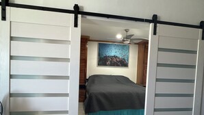 A bedroom with a bed, a ceiling fan, and a painting on the wall. - Beach Condo in Negril Jamaica (Negril)