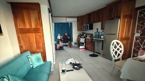A living room with a sofa, a coffee table, and a dining area with a table and chairs. - Beach Condo in Negril Jamaica (Negril)