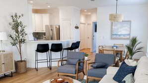 Ein modernes Wohnzimmer mit Sofa, Sesseln, einem Couchtisch und einem Essbereich mit Tisch und Stühlen.